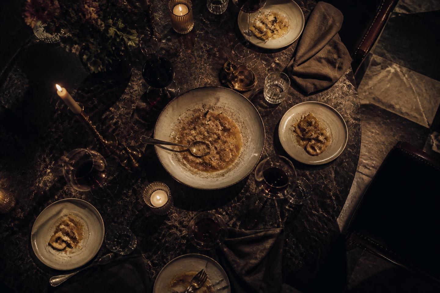 Mesa romana após o jantar, com massa, vinho Barolo e velas